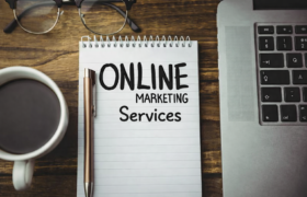 Online marketing services notebook on desk with coffee and laptop – digitalharsh